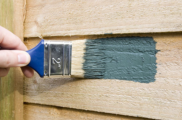 Paint being applied to a fence panel