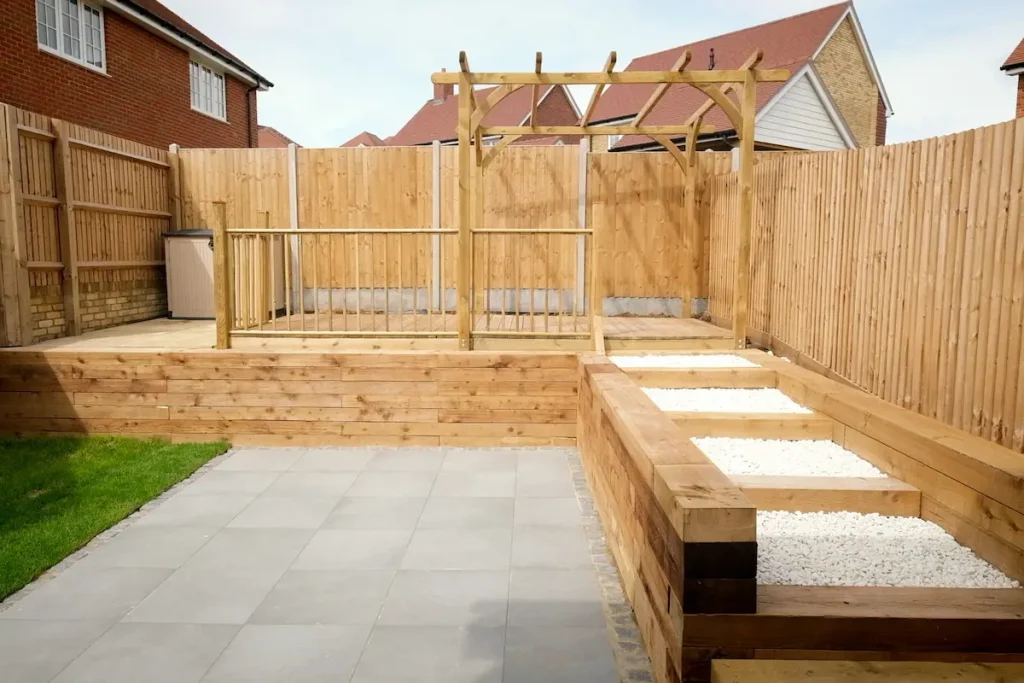 New-build garden with untreated wooden fencing pergola and decking