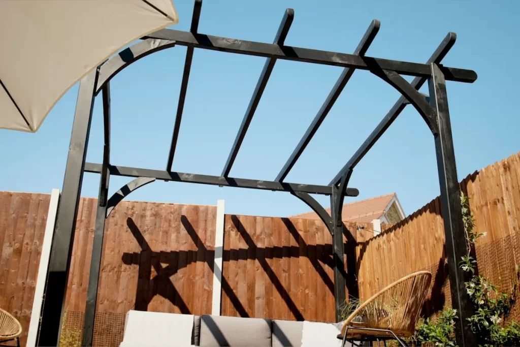 Finished black wooden pergola in a landscaped new-build garden