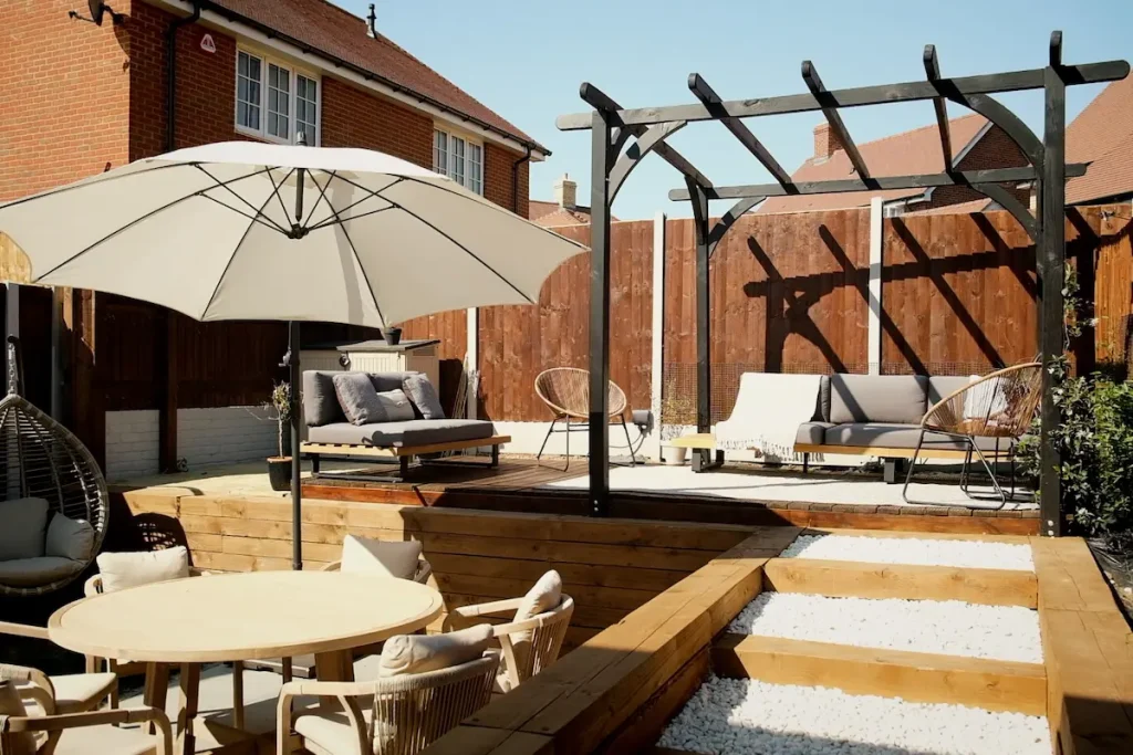 Completed garden makeover with stained fence black pergola and oiled decking
